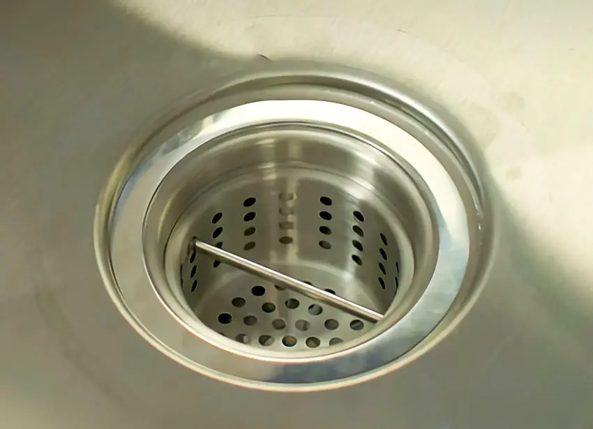 Sink waste arrestor catching food scraps in a family kitchen sink